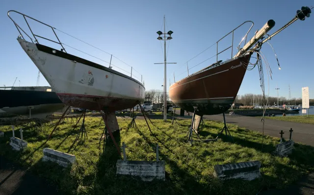 Boats on stands in a boatyard on a grass field