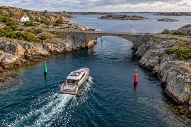A motor yacht approaching a bridge through a marked coastal channel