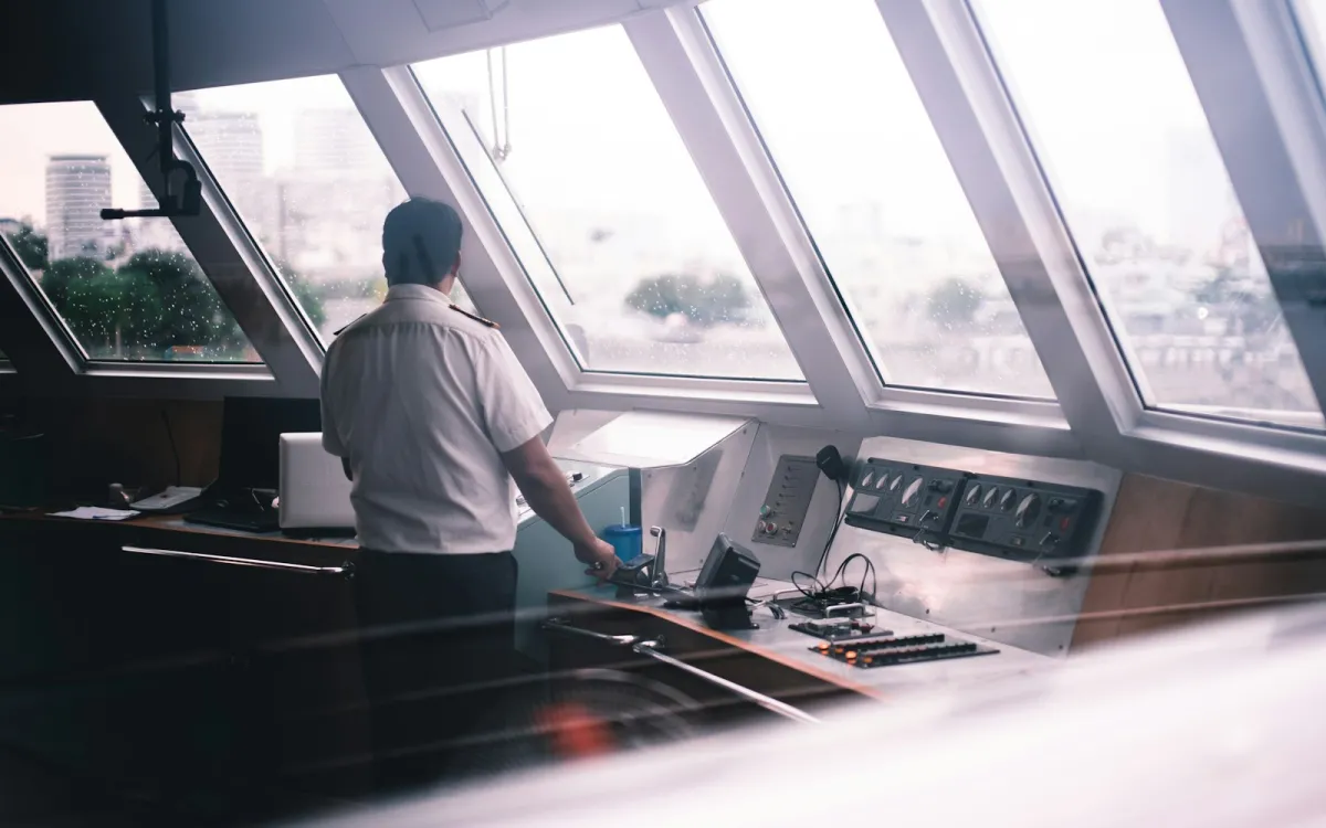 Captain standing at the helm station inside a yacht wheelhouse